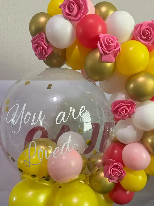 Pink, gold, yellow and white balloon garland with roses and a clear bubble balloon by CAJE Creations, Tampa FL